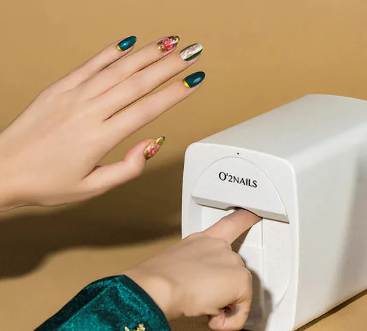 Compact artistic nail printer in use with vibrant nail designs.