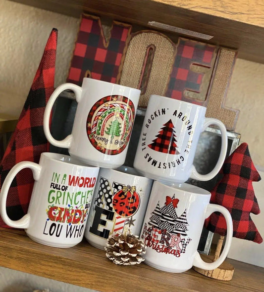 Christmas-themed 15oz ceramic coffee mugs on a festive shelf display.